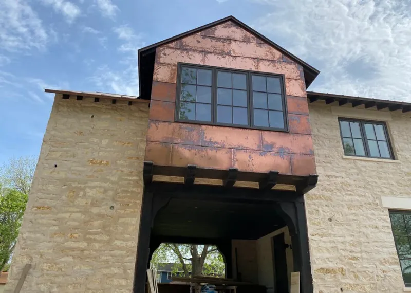 Copper metal panel facade on a stone building for Roof Repair in Benton